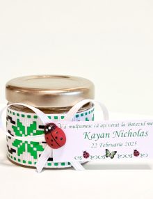 Borcanel cu miere naturală, decorat cu motive tradiționale și accesorizat cu fundă albă și buburuză decorativă. Ideal ca mărturie de botez, simbolizând dulceața și norocul. Perfect pentru a le oferi invitaților o amintire specială și elegantă.
